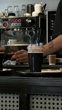 two people are making drinks at a coffee shop with espresso machines in the background