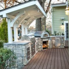 an outdoor bbq and grill area with wood flooring in front of a house