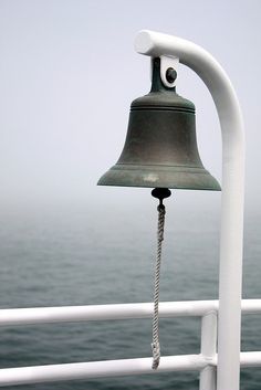 a bell on the side of a boat near the ocean