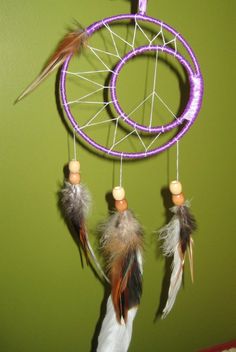 a purple and white dream catcher hanging on a wall next to a green painted wall