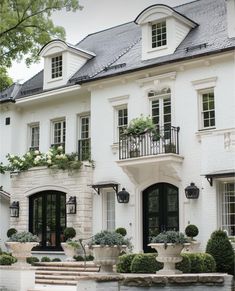 a large white house with lots of windows and plants on the balconies outside