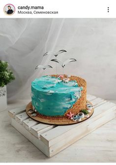 a cake with blue icing and seagulls on top is sitting on a wooden tray