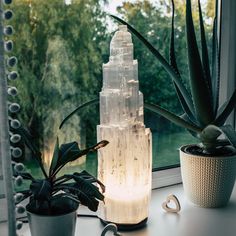 The Selenite Crystal Lamp is an exquisite and unique decoration piece that will bring a touch of elegance to any room. THese lamps measure between 8.25" up to 12" in height. This gorgeous lamp is made from natural selenite crystals, which are hand-crafted into a tower skyscraper shape. The light that illuminates through the shape of this lamp adds a calming glow to any room, making it an ideal choice for bedrooms, living rooms, dining rooms and more. Selenite, also known as Satin Spar, is a powe Crystals In House Decor, Plant And Crystal Decor, Salt Lamp Bedroom Aesthetic, Large Crystals Decor, Crystal House Decor, Crystal Wall Decor, Crystals Aesthetic Bedroom, Selenite Decor, Bedroom Lights Ideas