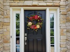 a black front door with a wreath on it