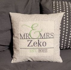 a pillow with the name and date on it is sitting on a bed next to two pillows