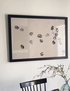 a vase with flowers sitting on top of a wooden table next to a framed painting