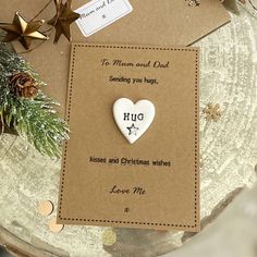 a white heart shaped brooch sitting on top of a brown card next to christmas decorations