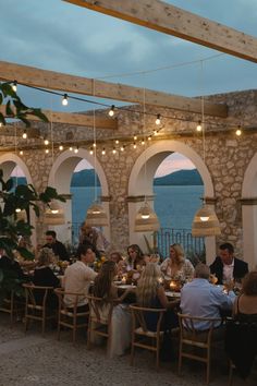 a group of people sitting around a table at a restaurant with lights hanging from the ceiling