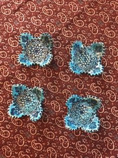 four small blue dishes sitting on top of a red tablecloth covered floor next to each other