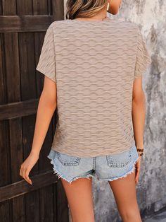 Bask in the effortless elegance of this beige textured top, designed to elevate your casual wardrobe with a touch of sophistication. The unique wave-like pattern adds a subtle yet captivating element to the design, making it a standout piece for any occasion. The relaxed fit and soft, breathable fabric ensure all-day comfort, perfect for warm summer days. The short sleeves and round neckline provide a classic silhouette that complements a variety of body types. Pair this top with your favorite d Textured Top, Bat Sleeve, Beige Top, Effortless Elegance, Wave Pattern, Classic Silhouette, Basic Style, Casual Wardrobe, Summer Days