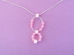 a pink necklace with two beads hanging from it's side on a purple background