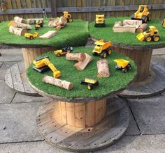 there are many toy trucks and tractors on the grass in this table made out of logs