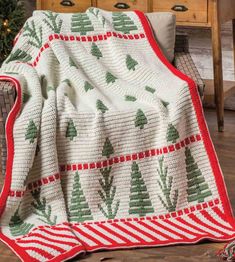 a white and red blanket sitting on top of a wooden floor next to a christmas tree