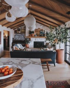 a living room filled with furniture next to a fire place under a wooden ceiling covered in hanging lights