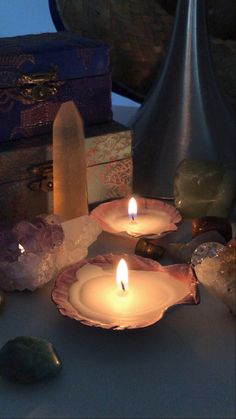 three candles sitting on top of a table next to rocks