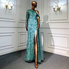 a mannequin dressed in a green dress with a slit through the skirt and one leg