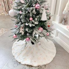 a white christmas tree with pink ornaments on it