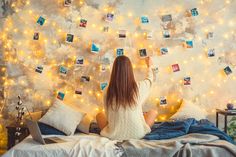 a woman is sitting on her bed and looking at the lights