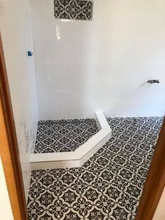 an empty bathroom with black and white tile on the floor, shower stall door open