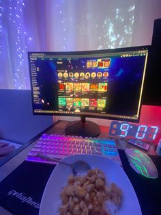 a computer monitor sitting on top of a desk next to a white plate with food