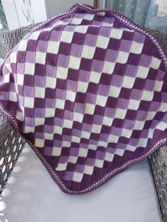 a purple and white blanket sitting on top of a wicker chair