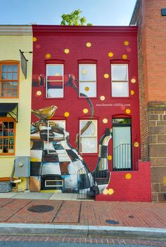 a large mural painted on the side of a building in front of a red brick building