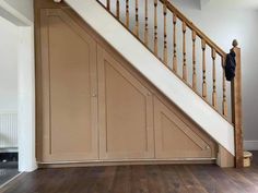 an empty room with wooden floors and white walls, under the stairs is a wood paneled stair case