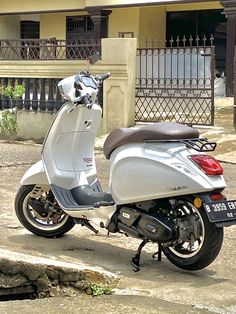 a white scooter parked on the side of a road in front of a building