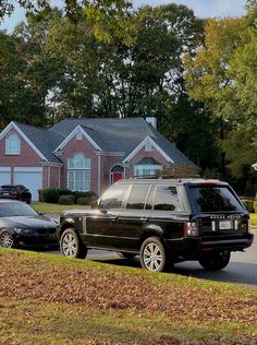 two cars parked in front of a house on the side of a road next to trees