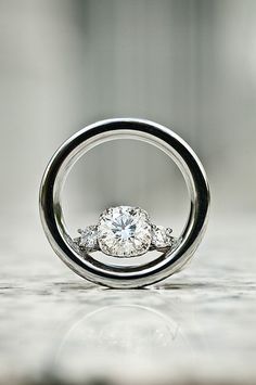 an engagement ring with three diamonds in it on top of a white countertop next to a wall