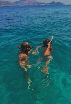 two people swimming in the ocean with their snorkels