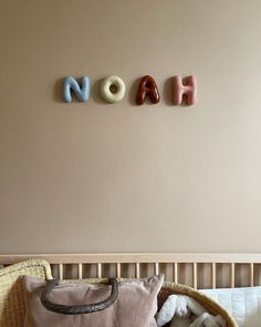 the name noah spelled in small letters above a crib with stuffed animals on it