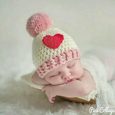 a newborn baby wearing a knitted hat with a heart on it's side