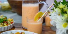 a table topped with plates and bowls of food next to a pitcher of orange juice