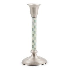 a silver candle holder with a green and white mosaic design on the top, in front of a white background