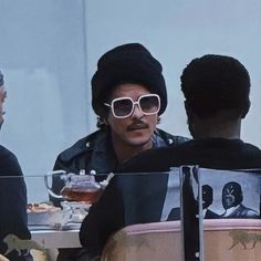 three men sitting at a table with food and drinks