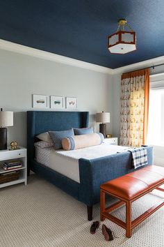 a blue and white bedroom with a bench in front of the bed, two lamps on either side