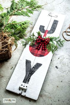 a wooden sign with the letter u on it is decorated with greenery and bow