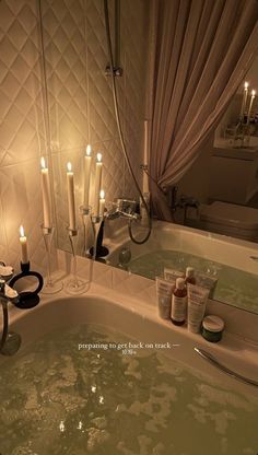 a bathtub filled with lots of candles next to a mirror