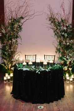 the table is set up with candles and greenery