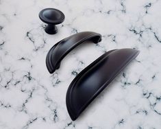 two black door handles sitting on top of a white marble counter next to each other