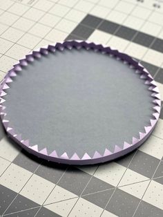 a round cake pan sitting on top of a checkered tablecloth covered in white and gray paper