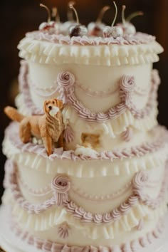 a three tiered wedding cake with an animal figurine on the top layer