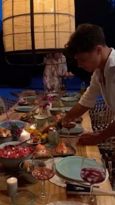 a group of people standing around a table covered in plates and bowls filled with food