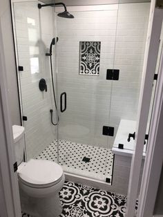 a bathroom with black and white tiles on the floor, shower stall and toilet area