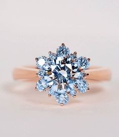 an engagement ring with a large blue diamond surrounded by smaller round diamonds on the band