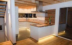 a kitchen with wooden flooring and white cabinets next to a staircase leading up to the second floor