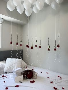 white balloons are suspended from the ceiling above a bed with red roses and petals on it