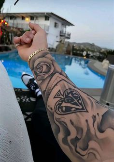 a person with a tattoo on their arm next to a swimming pool