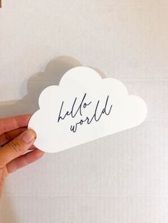 someone is holding up a white cloud with the word hello world written in black ink